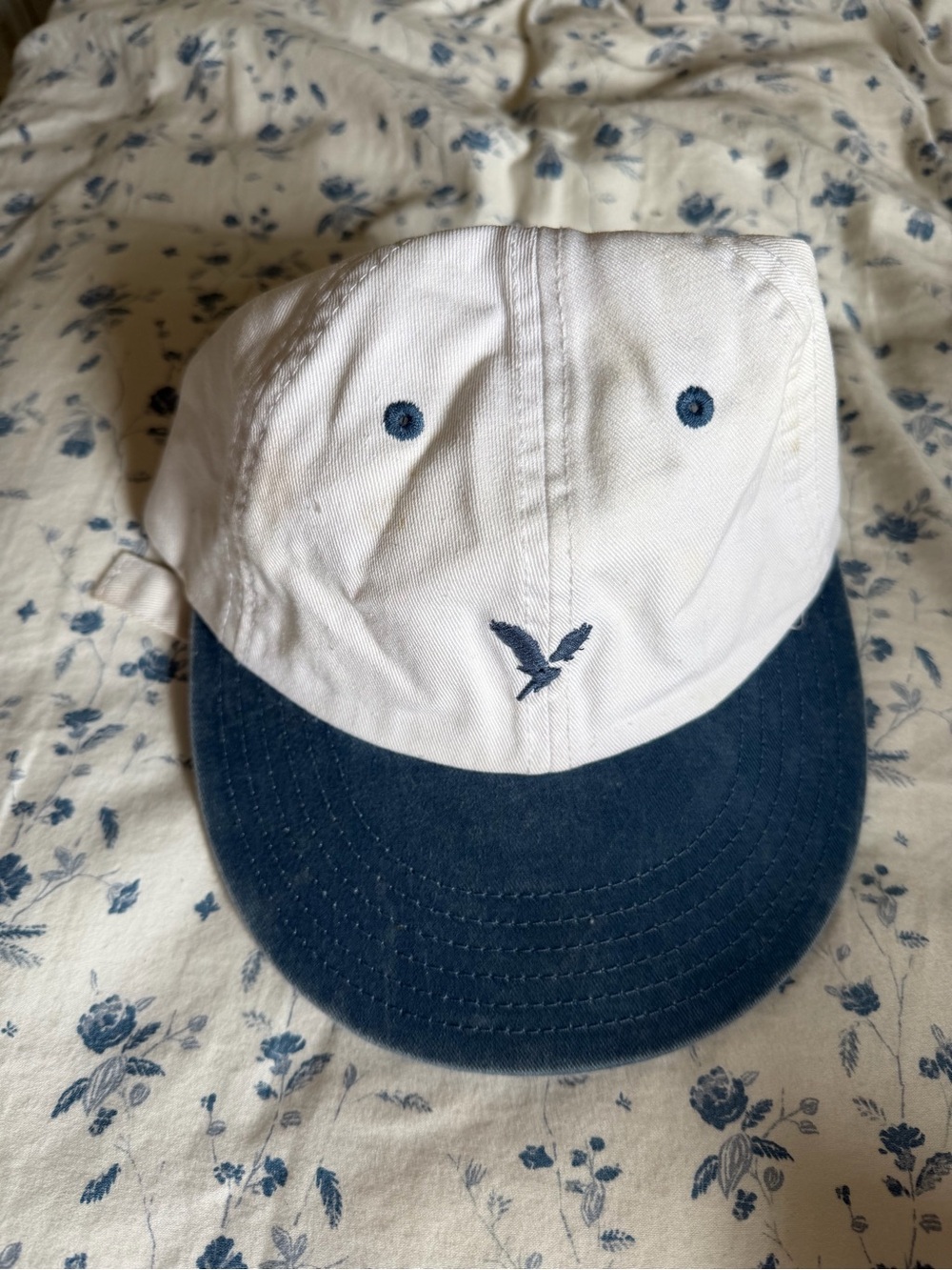 White and blue American Eagle cap with adjustable strap.